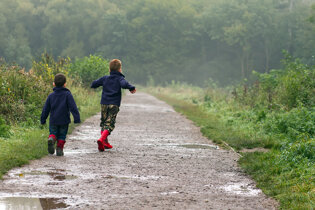Two kids running through puddles