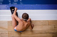 Boy sitting by pool with flippers
