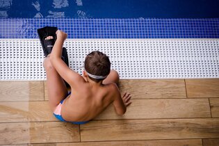 Boy sitting by pool with flippers