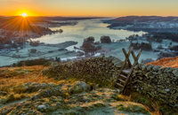 Wooden stile over stone wall with beautiful sunrise