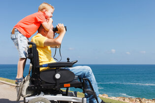 Father and son, in wheelchair at coast