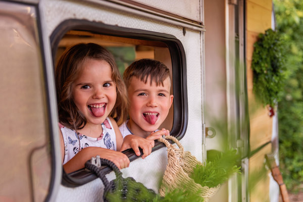 Kids love the novelty of staying somewhere new, make it an experience - image of happy kids look out of their caravan window