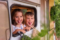 Kids love the novelty of staying somewhere new, make it an experience - image of happy kids look out of their caravan window