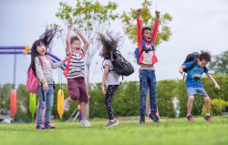 Group of mixed race children at kids club, jumping and playing