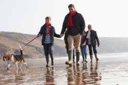 Family walking dog on beach.