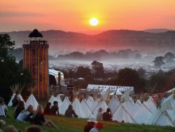 Glastonbury Festival at sunset with glamping accommodation in foreground [Credit: Getty]