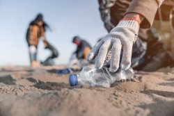 Women picking up plastic bottle on beach