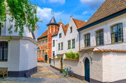 Beguinage Courtrai of Saint-Elisabeth, Begijnhof van Kortrijk with white houses and Sint-Annazaal museum, bicycles near wall on narrow cobblestone street in Kortrijk city historical centre, Belgium
