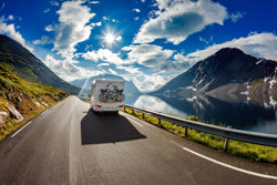 Caravan driving away from camera in mountain setting