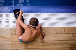 Boy sitting by pool with flippers