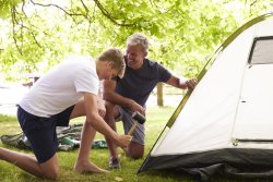 Father And Teenage Son Putting Up Tent On Camping