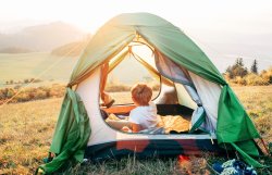Boy rest in tent and enjoy with sunset